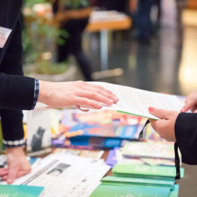 Man and Woman Sharing Information Leaflet over Exhibition Stand